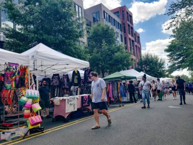 Açık hava sokak fuarında el yapımı eşyalar giyim mağazaları ve günlük şehir hayatı yer alıyor.