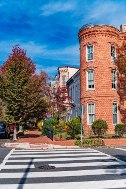 Dramatik bulutlu gökyüzü altında sonbahar ağaçları tarafından çerçevelenmiş tarihi tuğla evler.