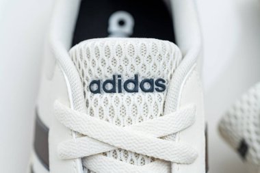 Beyaz spor ayakkabıların üzerindeki Adidas logosunun minimalist editoryal görüntüsü