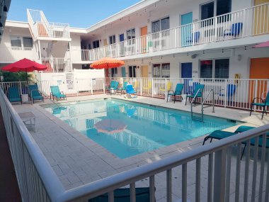 Renkli Sandalyeler ve Şemsiyelerle Retro Motel Avlusunda Açık Yüzme Havuzu