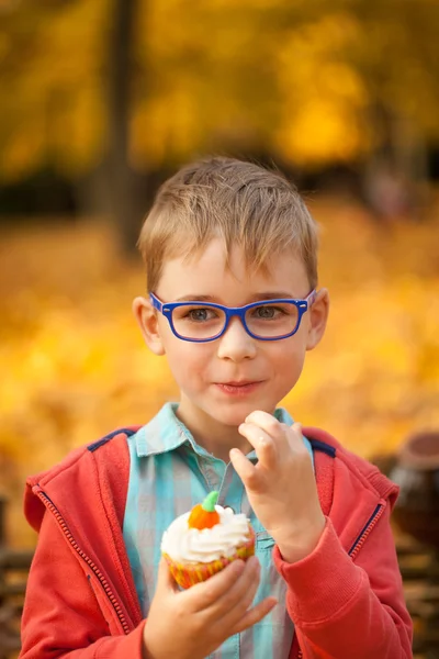 Genç çocuk sonbahar parkta tatlı kek yeme — Stok fotoğraf