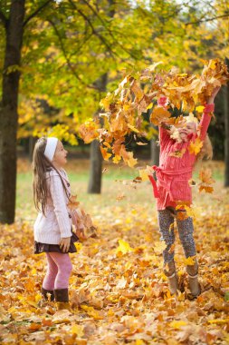 İki kız yaprakları sonbahar parkta atma