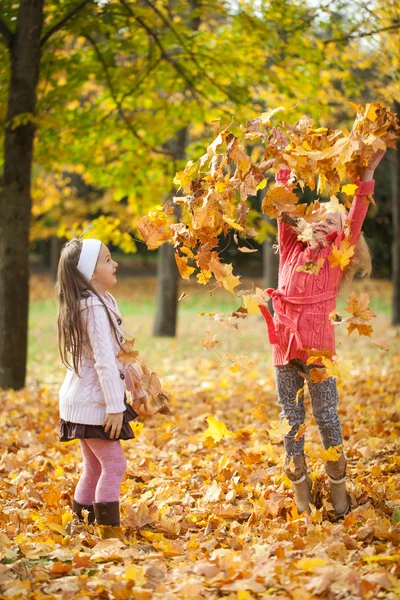 İki kız yaprakları sonbahar parkta atma