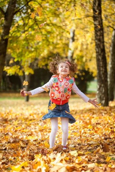 Junges Mädchen wirft Blätter in Herbstpark — Stockfoto