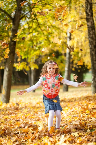 Junges Mädchen wirft Blätter in Herbstpark — Stockfoto