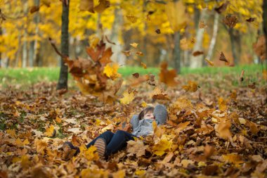 Genç kız yaprakları sonbahar parkta atma