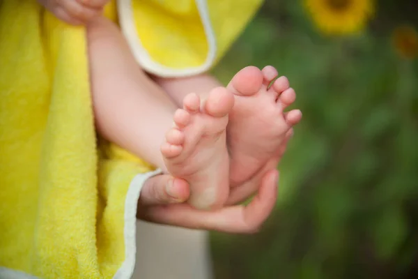 Niedliche Babyfüße Einem Gelben Frotteehandtuch Den Händen Der Mutter Sonnenblumen — Stockfoto