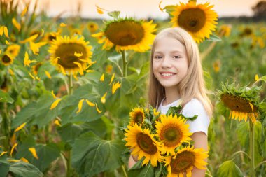 Sarı elbiseli, ayçiçeği tarlasında güzel bir genç kız.