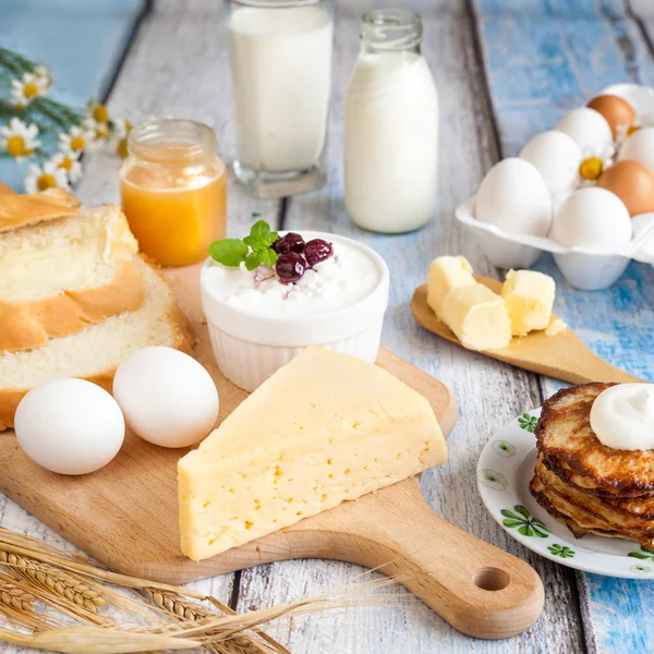 Mejeriprodukter, pannkakor, honung och färska ägg Stockfoto