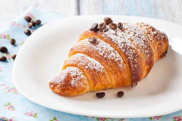 Croissant with coffee beans — Stock Photo, Image