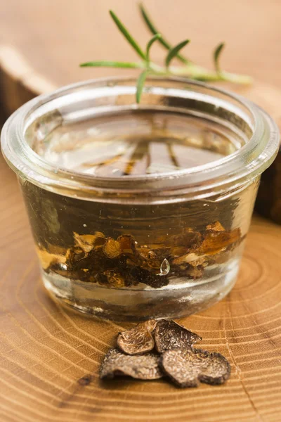 Trufa negra en rodajas en aceite de oliva en frasco pequeño y romero fresco — Foto de Stock