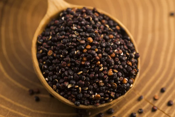 Sementes de quinoa preta em um fundo de madeira — Fotografia de Stock