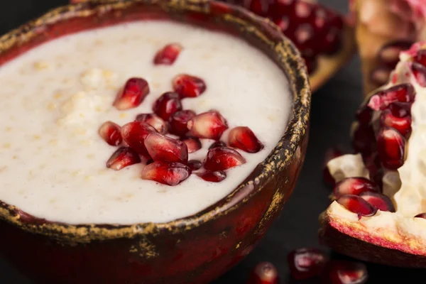 Dish of banana millet breakfast pudding with pomegranate — Stock Photo, Image