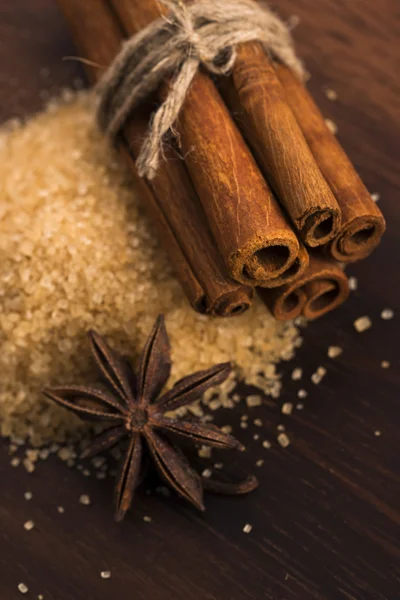 Cinnamon sticks with pure cane brown sugar on wood background — Stock Photo, Image