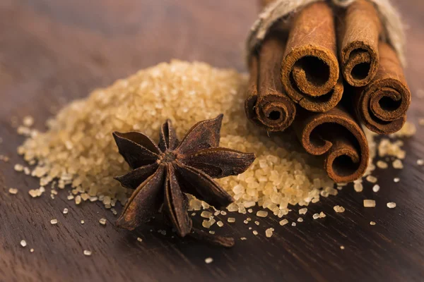 Cinnamon sticks with pure cane brown sugar on wood background — Stock Photo, Image