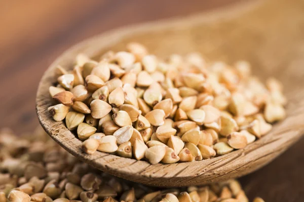 Buckwheat with a spoon on a wooden boards background — Stock Photo, Image