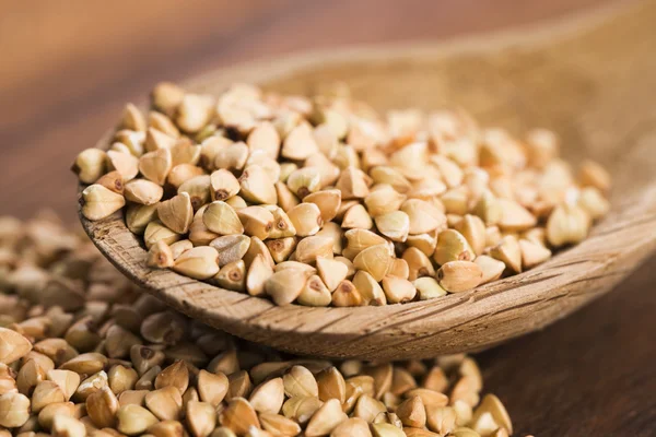 Buckwheat with a spoon on a wooden boards background — Stock Photo, Image