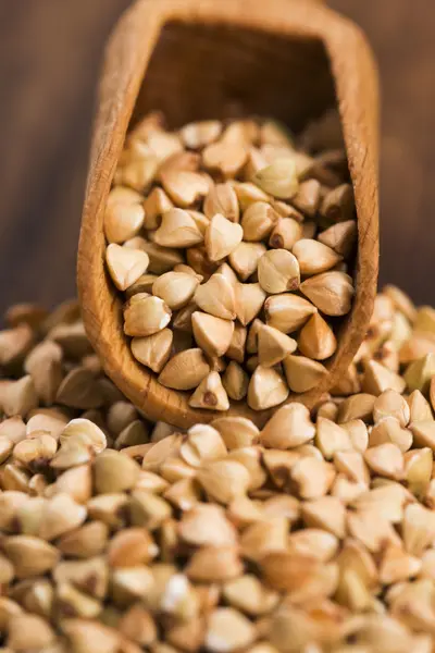 Buckwheat with a spoon on a wooden boards background — Stock Photo, Image