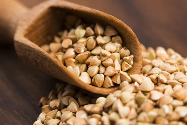 Buckwheat with a spoon on a wooden boards background — Stock Photo, Image