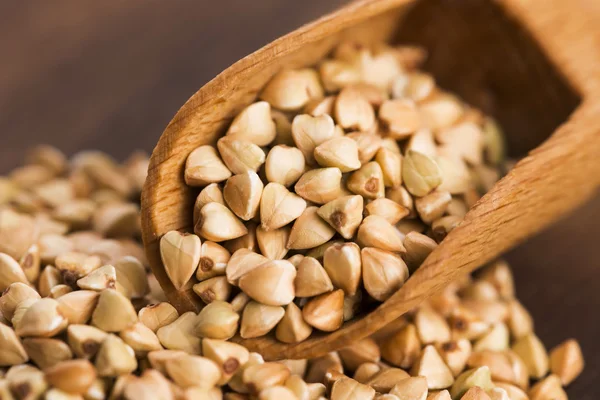 Buckwheat with a spoon on a wooden boards background — Stock Photo, Image