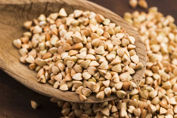 Buckwheat with a spoon on a wooden boards background — Stock Photo, Image