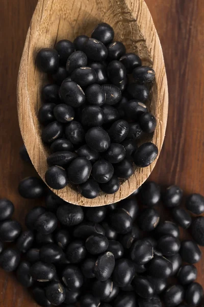 A lot of black soybeans on wooden background — Stock Photo, Image