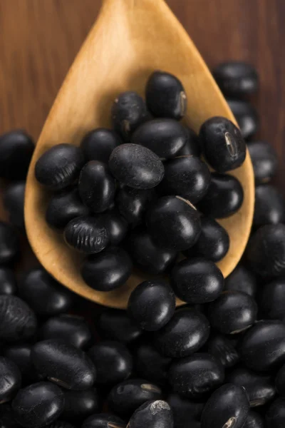 A lot of black soybeans on wooden background — Stock Photo, Image