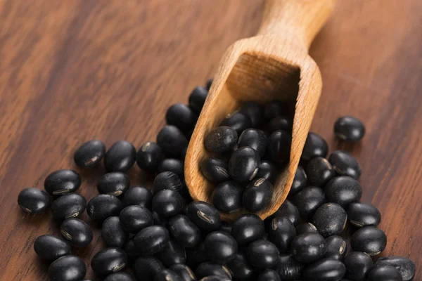 A lot of black soybeans on wooden background — Stock Photo, Image