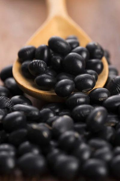 A lot of black soybeans on wooden background — Stock Photo, Image