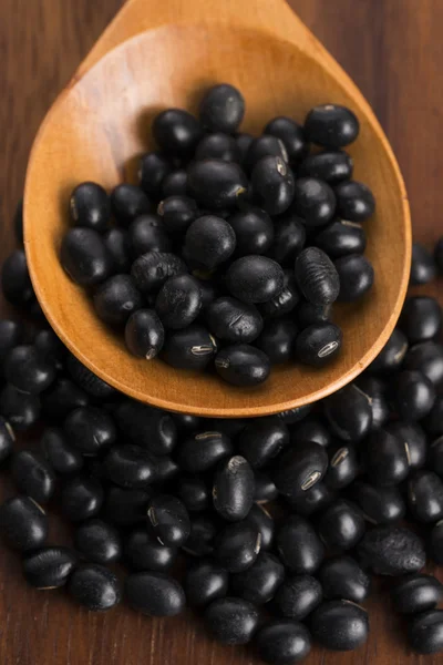 A lot of black soybeans on wooden background — Stock Photo, Image