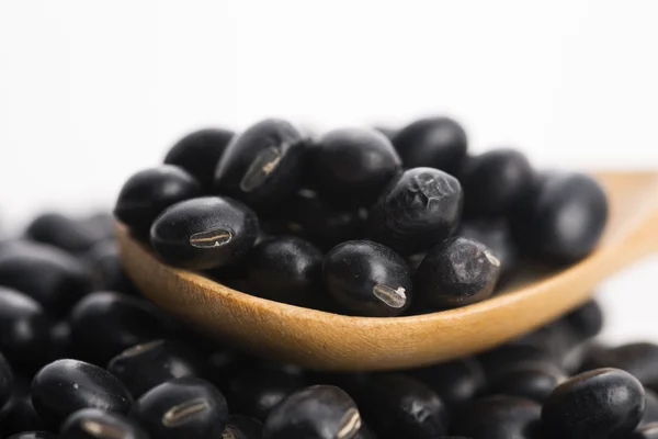 A lot of black soybeans on wooden background — Stock Photo, Image