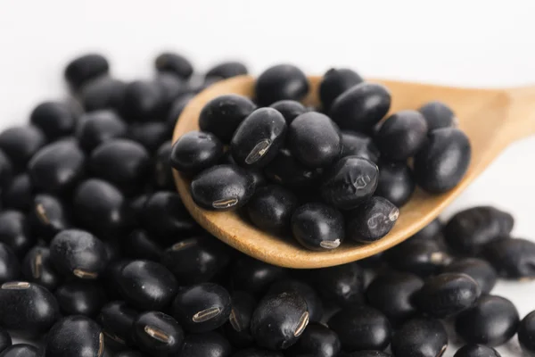 A lot of black soybeans on wooden background — Stock Photo, Image
