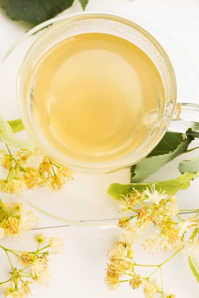 Teapot and cup with linden tea and flowers — Stock Photo, Image