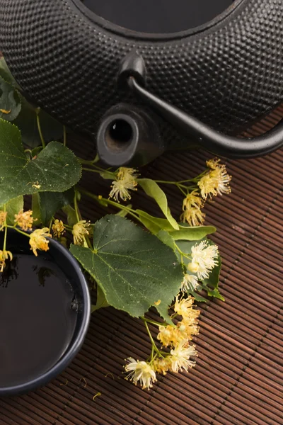 Çaydanlık ve bardak ıhlamur çayı ve çiçeklerle — Stok fotoğraf