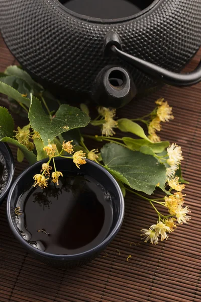 Teekanne und Tasse mit Lindentee und Blumen — Stockfoto