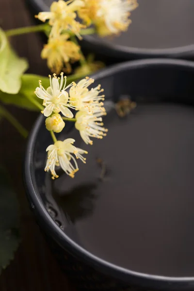 Tetera y taza con té de tilo y flores — Foto de Stock