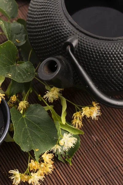 Bule e xícara com chá de tília e flores — Fotografia de Stock