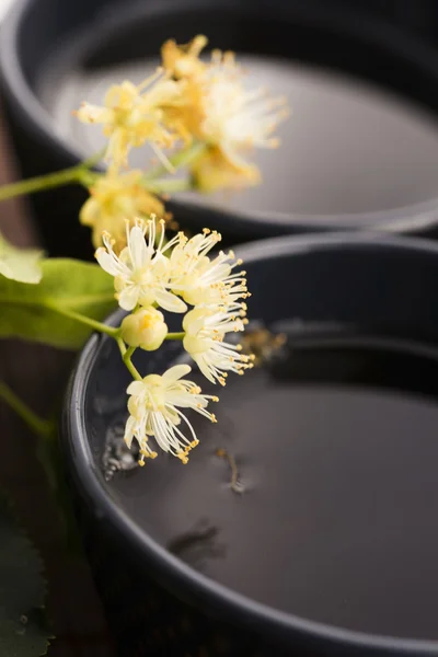 Tetera y taza con té de tilo y flores —  Fotos de Stock