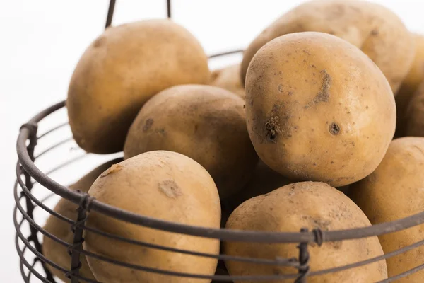 Uncooked potatoes in wire basket — Stock Photo, Image