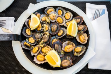 grilled limpets served with lemon clipart