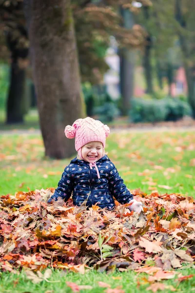 Glückliches kleines Mädchen, das mit Blättern spielt — Stockfoto