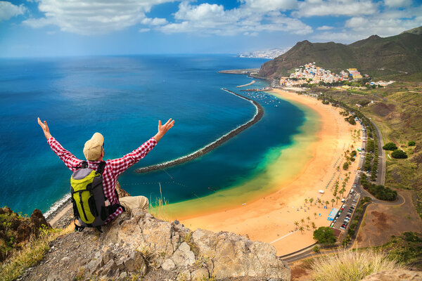 man sitting on the edge of a cliff, enjoying view of Playa de La