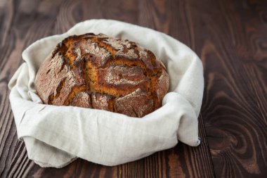 Taze pişmiş çavdar ekmeği ahşap bir arka planda keten kumaş içinde daire şeklinde.