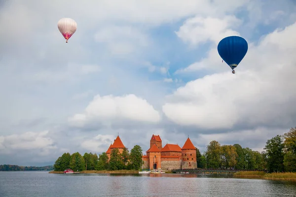 リトアニアのトラカイ島にあるトラカイ島城の美しい景色 ガルヴェ湖の島 そして上空を飛ぶ2つの気球 — ストック写真