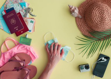 Covid-19 salgınından sonra eli hijyenik bir maskeyle gezginlerin eşyalarıyla dolu. İnsanlar Covid-19 kısıtlamalarından yoruldu. Yeni normal kavram.