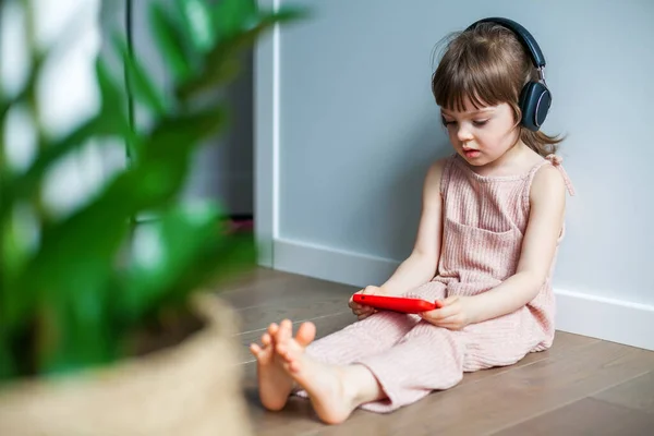 Söt Liten Flicka Med Stora Hörlurar Och Mobiltelefon Sitter Ensam — Stockfoto