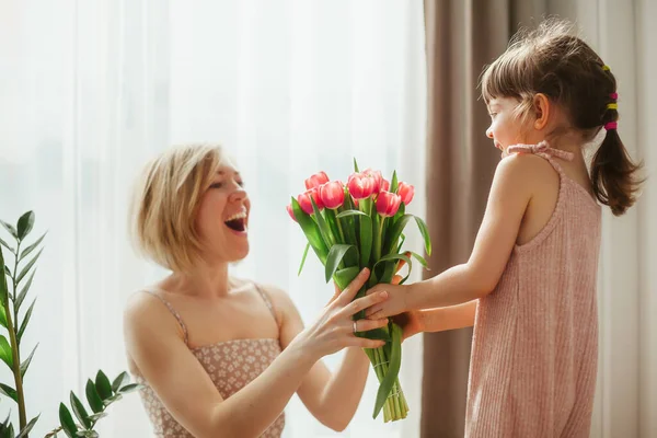 母亲节快乐 小女孩祝贺她的母亲 并送给她鲜花 妈妈和女儿在一起 专注于郁金香 — 图库照片