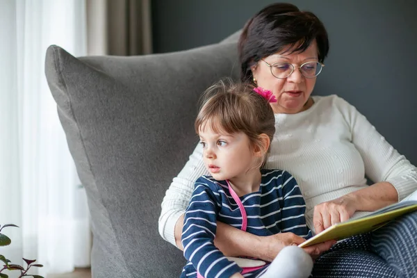 Mała Dziewczynka Jej Babcia Spędzają Razem Czas Czytając Książkę Siedząc — Zdjęcie stockowe