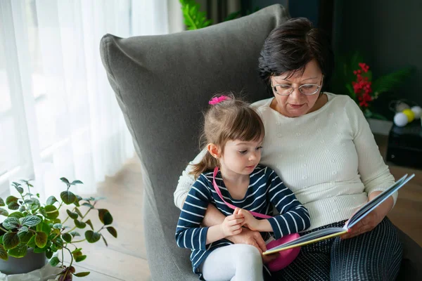 Grandmother Hugging Her Little Granddaughter Reading Book Her Granny Telling — Stok fotoğraf