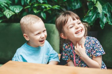 İki sevimli gülen çocuk - arkadaşlar ya da kız kardeşler - evde oturuyorlar.